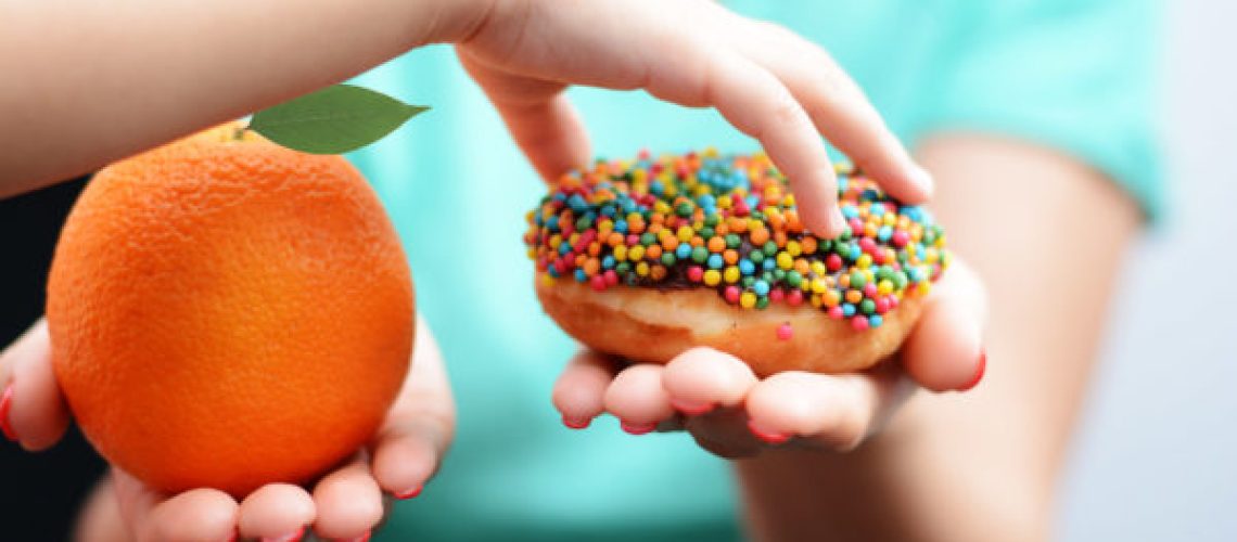 Child obesity concept with little girl hand choosing a sweet and