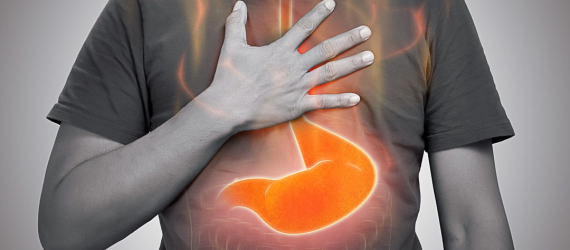 A man burning sensation in chest from acid reflux on gray background.