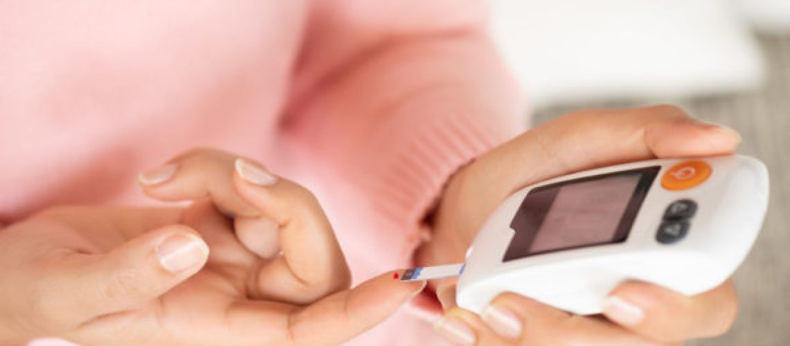 Close up of woman hands checking blood sugar level by Glucose meter for diabetes tester using as Medicine, glycemia, healthcare and medical concept.