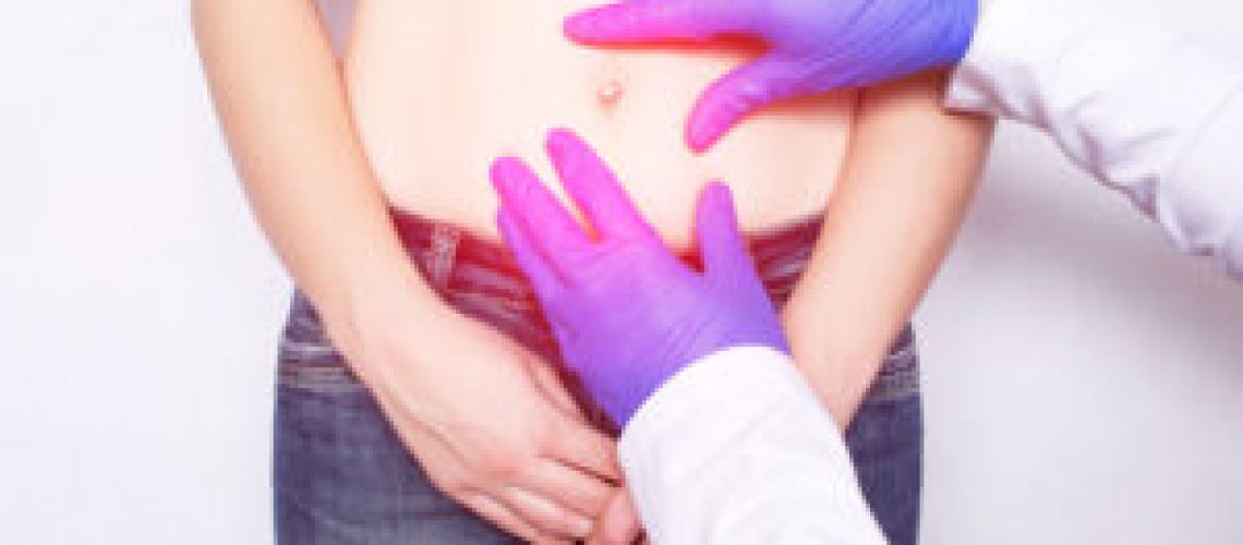 The doctor conducts a medical examination of the patient's girl whose abdominal pain, umbilical hernia of the abdomen, paraumbilical, discomfort